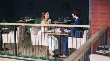 一对漂亮的夫妻正在餐馆里享受约会，这时男人正在向女孩求婚，给她求婚